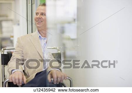 Smiling businessman sitting in office View Large Photo Image Stock Image - Smiling businessman sitting in office. Fotosearch
