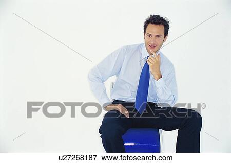 Smiling businessman sitting on chair View Large Photo Image Stock Photo - Smiling businessman sitting on chair. Fotosearch