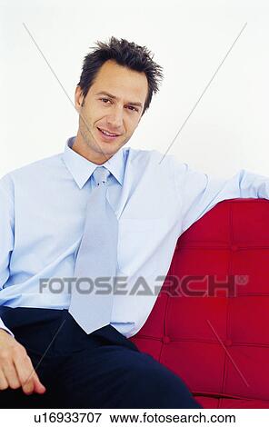 Smiling businessman sitting on couch View Large Photo Image Stock Photo - Smiling businessman sitting on couch. Fotosearch