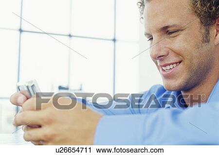 Stock Image - Smiling businessman using cell phone. Fotosearch