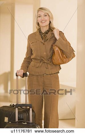 Smiling businesswoman rolling luggage View Large Photo Image Stock Image - Smiling businesswoman rolling luggage. Fotosearch