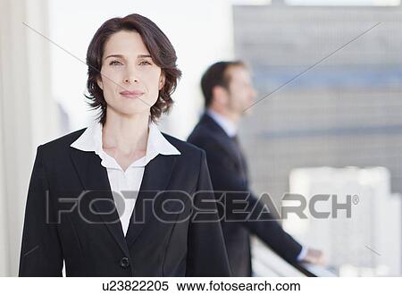 Stock Photography - Smiling businesswoman standing in office. Fotosearch