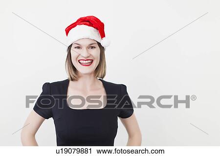Stock Image - Smiling businesswoman wearing Santa hat. Fotosearch