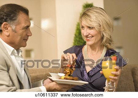 Stock Photo - Smiling couple eating hors d’ouerves. Fotosearch