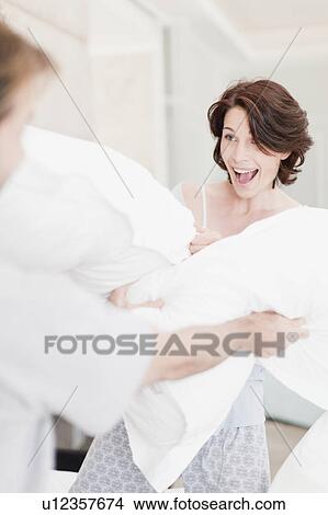 Smiling couple having pillow fight View Large Photo Image Picture - Smiling couple having pillow fight. Fotosearch