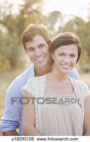Stock Photo - Smiling couple hugging outdoors. Fotosearch