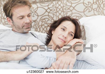 Stock Photo - Smiling couple relaxing in bed. Fotosearch