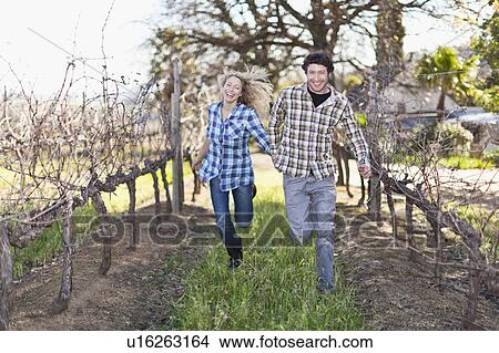 Smiling couple running in vineyard View Large Photo Image Picture - Smiling couple running in vineyard. Fotosearch