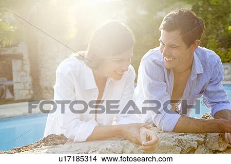 Smiling couple talking by pool View Large Photo Image Picture - Smiling couple talking by pool. Fotosearch