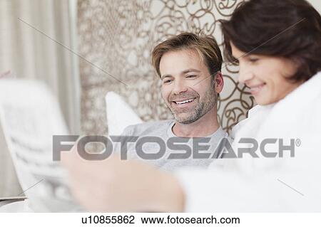 Stock Image - Smiling couple using laptop in bed. Fotosearch