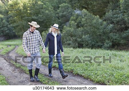 Smiling couple walking on dirt path View Large Photo Image Stock Image - Smiling couple walking on dirt path. Fotosearch