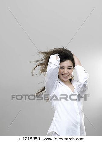 Stock Photo - Smiling girl playing with her hair. Fotosearch