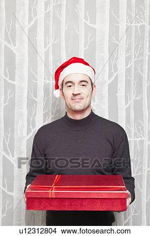 Smiling man in Santa hat with gift View Large Photo Image Picture - Smiling man in Santa hat with gift. Fotosearch