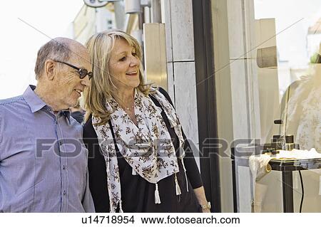Smiling older couple window shopping View Large Photo Image Picture - Smiling older couple window shopping. Fotosearch
