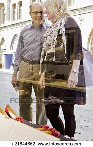 Stock Image - Smiling older couple window shopping. Fotosearch