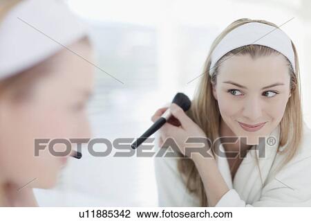 Stock Image - Smiling woman applying makeup. Fotosearch