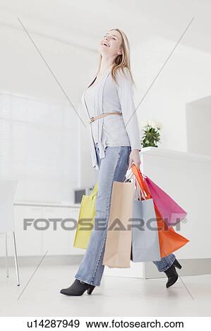 Stock Photo - Smiling woman carrying shopping bags. Fotosearch