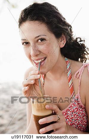 Smiling woman drinking through straw View Large Photo Image Stock Image - Smiling woman drinking through straw. Fotosearch