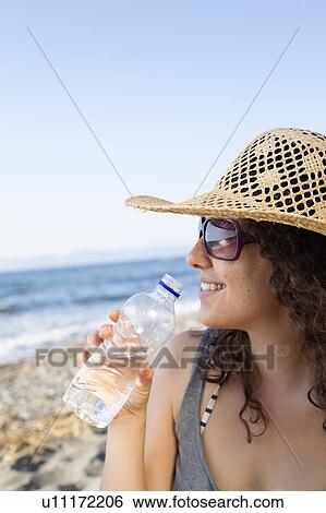 Smiling woman drinking water on beach View Large Photo Image Stock Photograph - Smiling woman drinking water on beach. Fotosearch