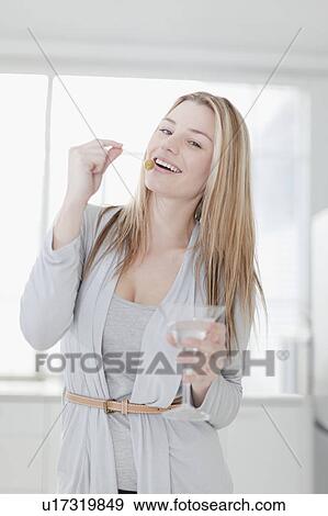 Smiling woman eating olive in drink View Large Photo Image Stock Photo - Smiling woman eating olive in drink. Fotosearch