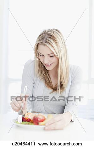 Stock Image - Smiling woman eating plate of food. Fotosearch
