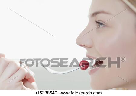 Stock Image - Smiling woman eating raspberry. Fotosearch