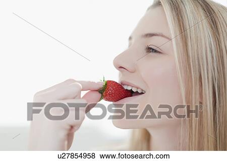 Stock Photo - Smiling woman eating strawberry. Fotosearch
