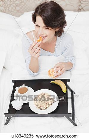 Stock Photography - Smiling woman having breakfast in bed. Fotosearch