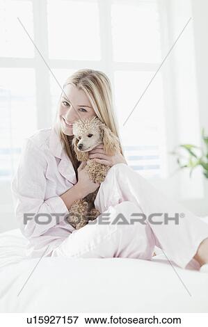 Smiling woman hugging dog on bed View Large Photo Image Stock Photo - Smiling woman hugging dog on bed. Fotosearch