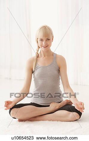 Stock Image - Smiling woman meditating cross-legged. Fotosearch