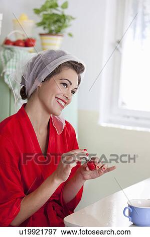 Stock Photo - Smiling woman painting her nails. Fotosearch