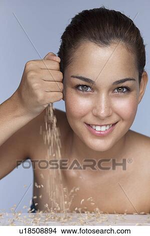 Picture - Smiling woman pouring handful of grains. Fotosearch