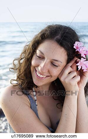 Smiling woman putting flower in her hair View Large Photo Image Stock Photo - Smiling woman putting flower in her hair. Fotosearch