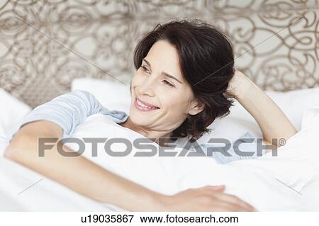 Smiling woman sitting up in bed View Large Photo Image Stock Photo - Smiling woman sitting up in bed. Fotosearch