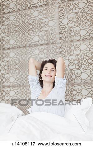 Smiling woman stretching in bed View Large Photo Image Stock Photo - Smiling woman stretching in bed. Fotosearch