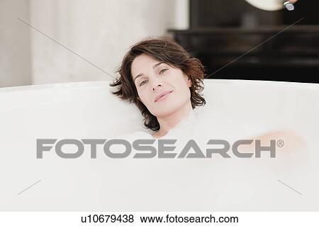 Stock Photo - Smiling woman taking bubble bath. Fotosearch