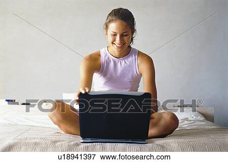 Smiling woman using laptop on bed View Large Photo Image Stock Photo - Smiling woman using laptop on bed. Fotosearch
