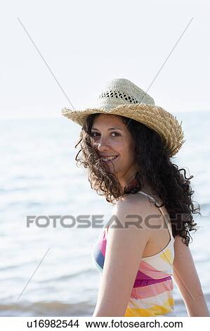 Picture - Smiling woman wearing sunhat on beach. Fotosearch