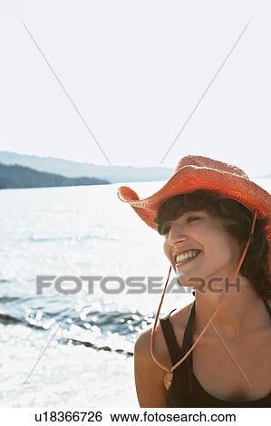 Stock Photograph - Smiling woman wearing sunhat on beach. Fotosearch