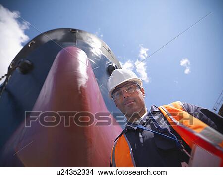 Picture - Smiling worker standing by ship. Fotosearch