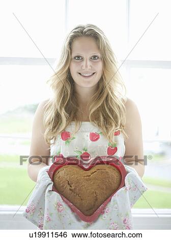 Stock Photograph - Teenage girl holding heart shaped cake. Fotosearch