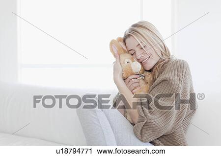 Stock Image - Teenage girl hugging stuffed toy. Fotosearch