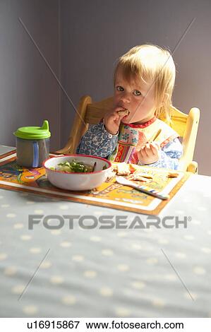 Toddler girl eating at table View Large Photo Image Stock Photo - Toddler girl eating at table. Fotosearch