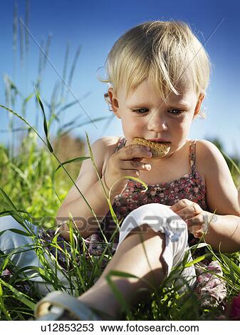 Toddler girl eating cracker in grass View Large Photo Image Stock Image - Toddler girl eating cracker in grass. Fotosearch