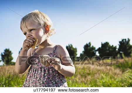 Toddler girl eating crackers outdoors View Large Photo Image Stock Photo - Toddler girl eating crackers outdoors. Fotosearch