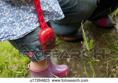 Stock Image - Toddler girl holding dirty shovel. Fotosearch