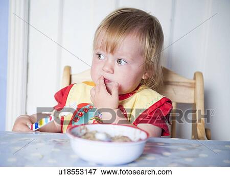 Toddler girl in bib eating at table View Large Photo Image Stock Photo - Toddler girl in bib eating at table. Fotosearch