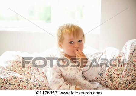 Stock Image - Toddler girl sitting in bed. Fotosearch