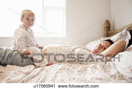 Toddler girl sitting with mother in bed View Large Photo Image Stock Image - Toddler girl sitting with mother in bed. Fotosearch