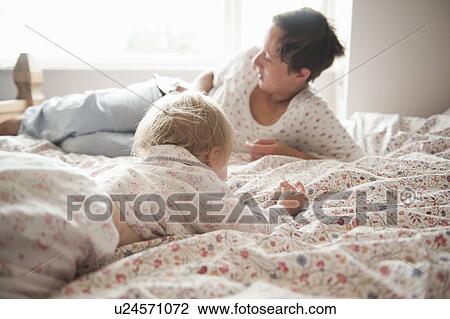 Stock Image - Toddler girl sitting with mother in bed. Fotosearch